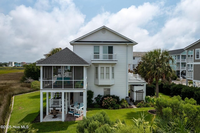 back of property featuring a lawn, a patio area, and a sunroom