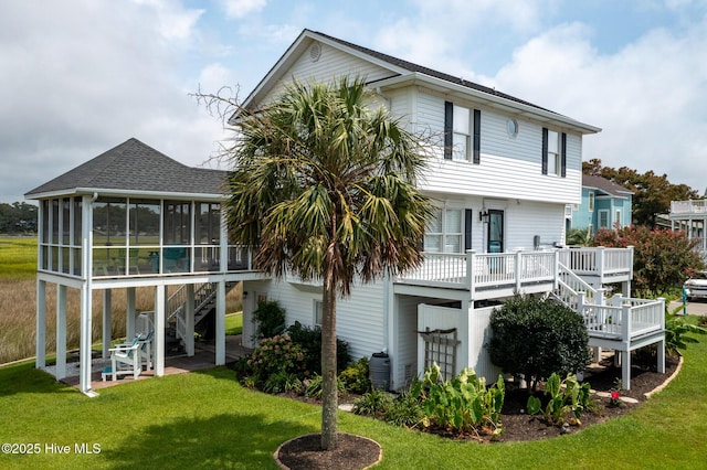 back of property featuring a wooden deck, a sunroom, and a lawn