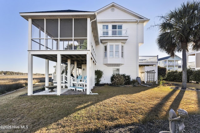 view of front of home featuring a balcony, a front yard, and a sunroom