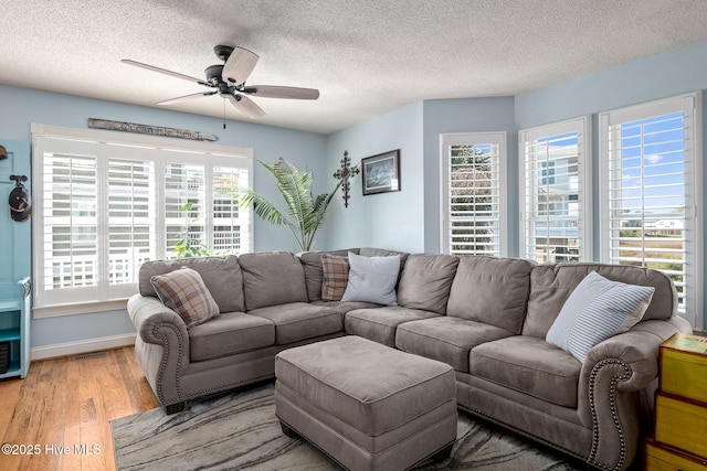 living room with ceiling fan, wood-type flooring, and a textured ceiling