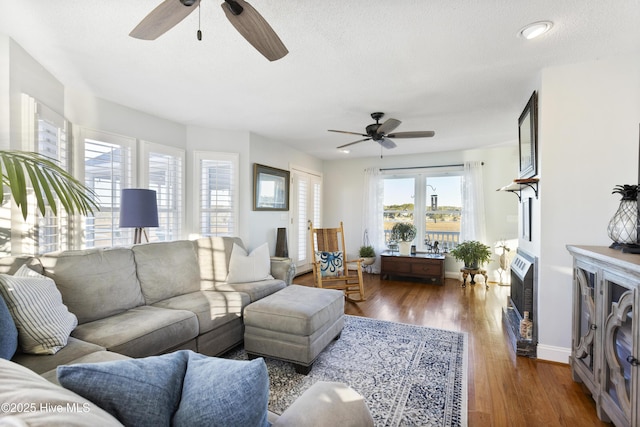 living room with ceiling fan, dark wood-type flooring, and a textured ceiling