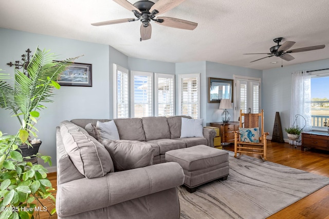 living room featuring ceiling fan, french doors, a textured ceiling, and hardwood / wood-style floors