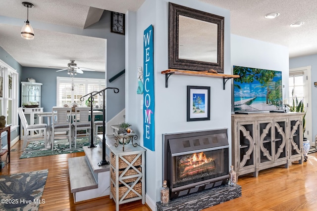 interior space with a textured ceiling, ceiling fan, and hardwood / wood-style floors