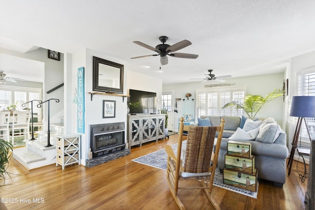 living room with ceiling fan, wood-type flooring, and a textured ceiling