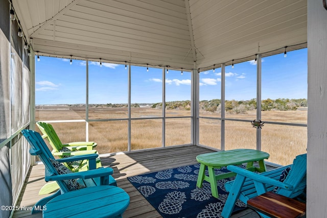 sunroom with lofted ceiling and a rural view