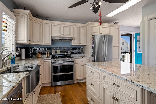 kitchen featuring a textured ceiling, ceiling fan, stainless steel appliances, and cream cabinets