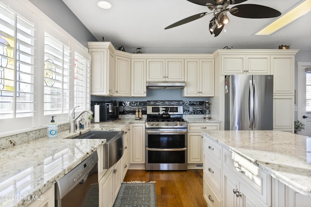 kitchen featuring light stone counters, sink, appliances with stainless steel finishes, and a healthy amount of sunlight