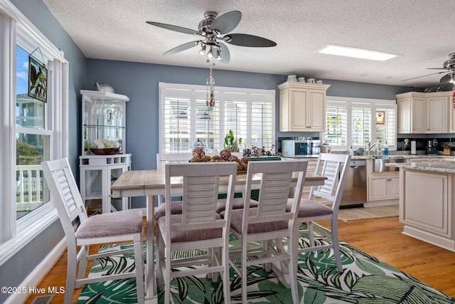 kitchen with cream cabinetry, light stone countertops, stainless steel appliances, and light hardwood / wood-style floors