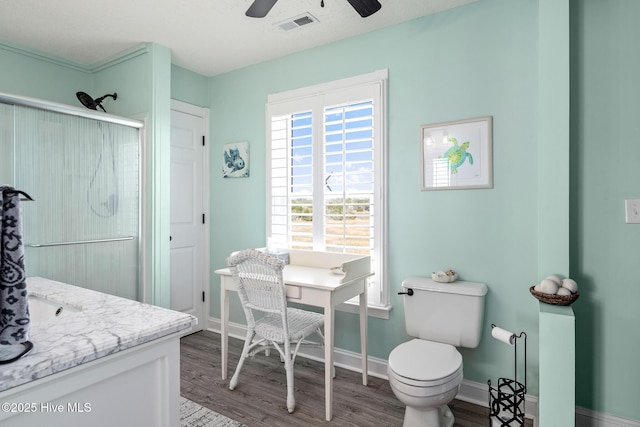 bathroom featuring toilet, ceiling fan, wood-type flooring, an enclosed shower, and vanity