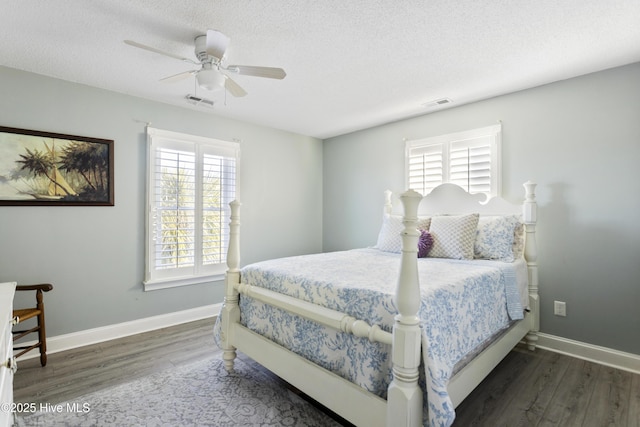 bedroom with ceiling fan, dark hardwood / wood-style flooring, and a textured ceiling