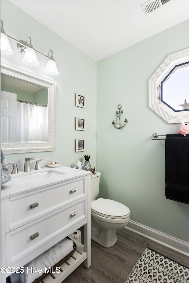 bathroom with hardwood / wood-style floors, toilet, and vanity