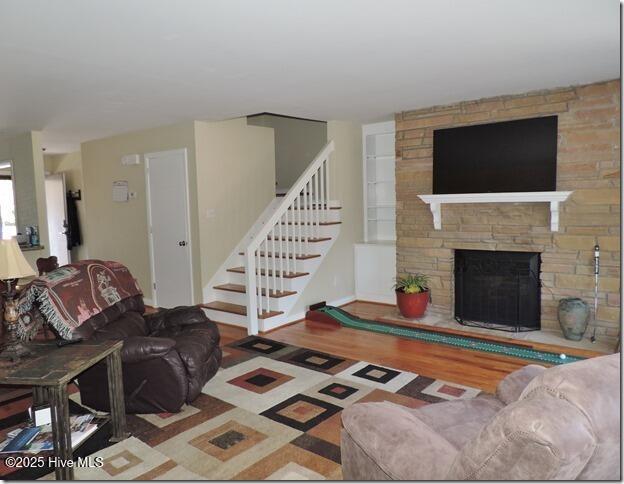 living room featuring hardwood / wood-style floors, built in features, and a fireplace