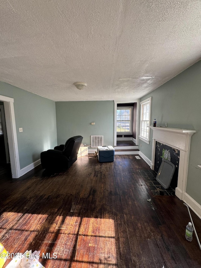 unfurnished room featuring a fireplace, a textured ceiling, and dark hardwood / wood-style flooring