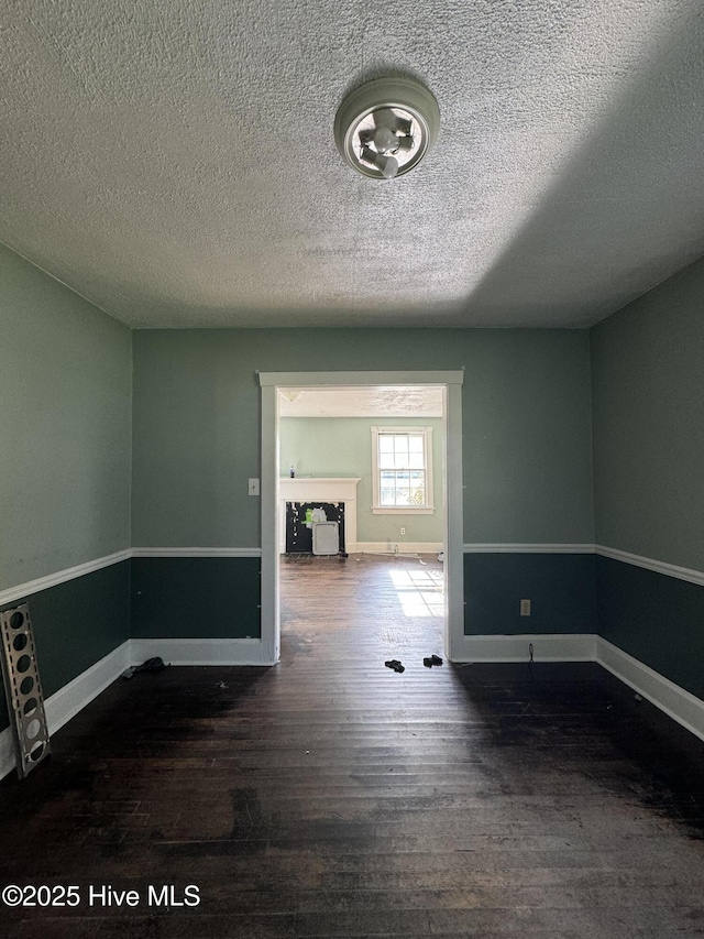 unfurnished room featuring a textured ceiling and dark wood-type flooring