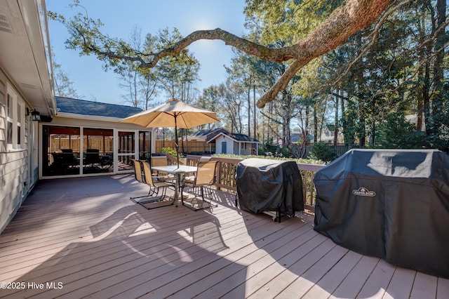 wooden deck featuring an outbuilding and a grill