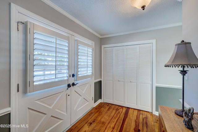 doorway to outside featuring ornamental molding, wood-type flooring, and a textured ceiling