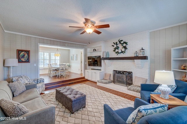 living room with hardwood / wood-style floors, built in features, a fireplace, crown molding, and a textured ceiling