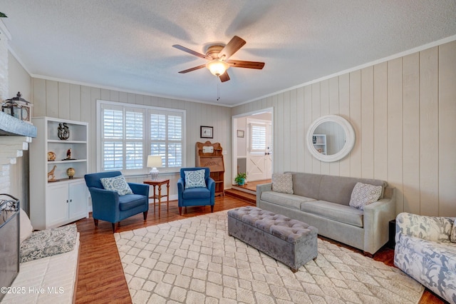 living room with wood-type flooring, a healthy amount of sunlight, a textured ceiling, and a fireplace