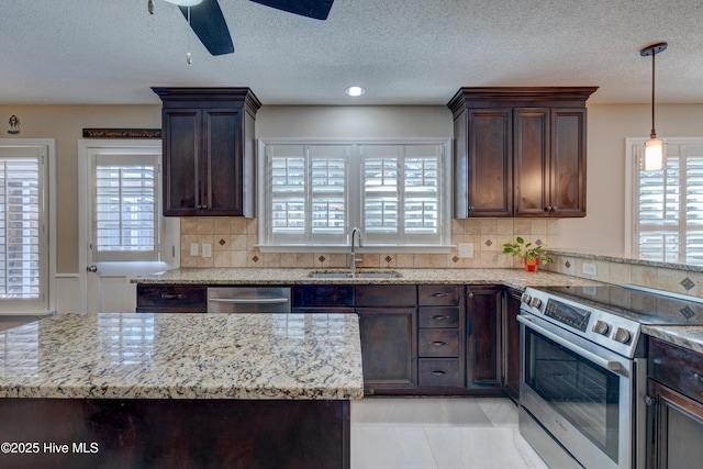 kitchen featuring stainless steel appliances, light stone countertops, sink, and dark brown cabinets