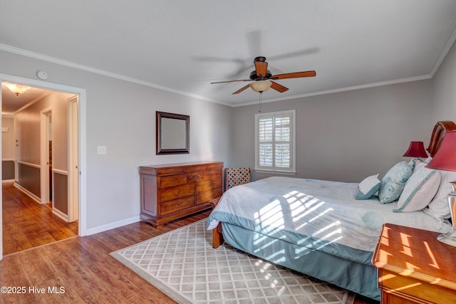 bedroom with hardwood / wood-style flooring, ornamental molding, and ceiling fan