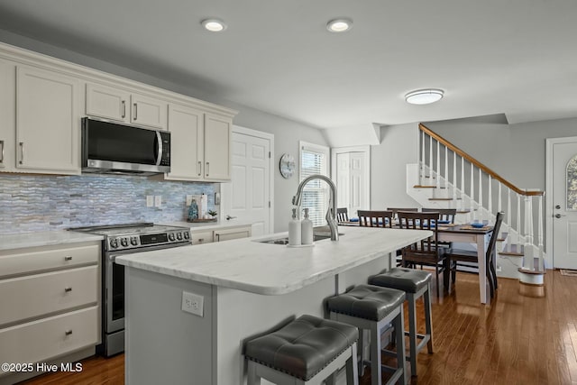 kitchen with white cabinetry, appliances with stainless steel finishes, a center island with sink, and sink