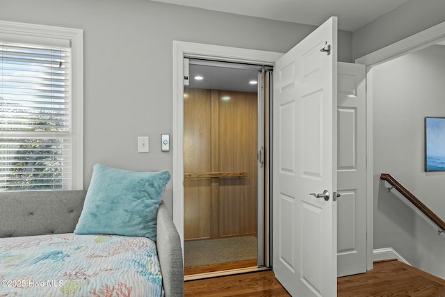 bedroom with a closet, wood-type flooring, and elevator