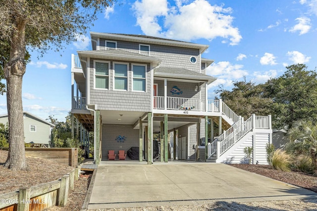 raised beach house featuring covered porch and a carport