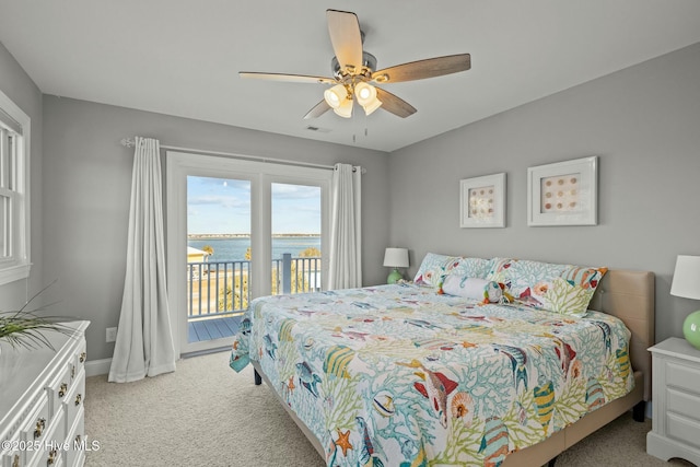 bedroom with ceiling fan, light colored carpet, access to outside, and a water view