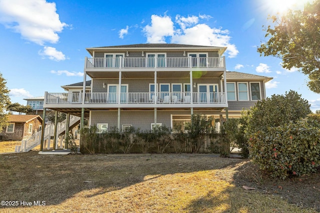 back of property with a yard and a balcony