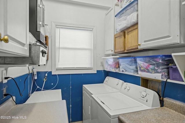 washroom featuring cabinets and washer and clothes dryer