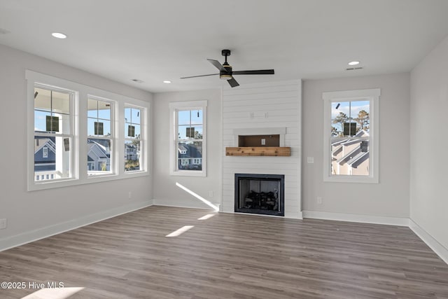 unfurnished living room with ceiling fan, wood-type flooring, and a fireplace