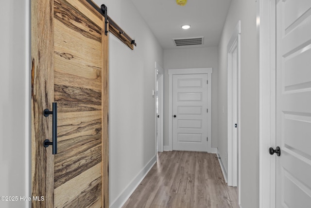 hall featuring light wood-type flooring and a barn door