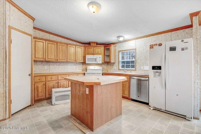 kitchen featuring white appliances, a kitchen island, ornamental molding, and sink