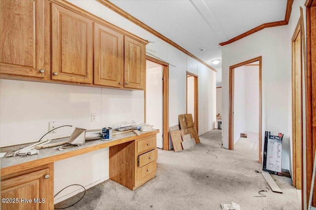 home office featuring built in desk, light carpet, and crown molding