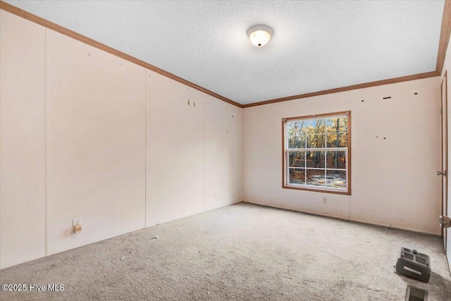 unfurnished room featuring a textured ceiling, ornamental molding, and carpet flooring