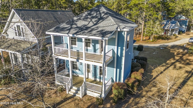 exterior space featuring a porch, a balcony, and a shingled roof