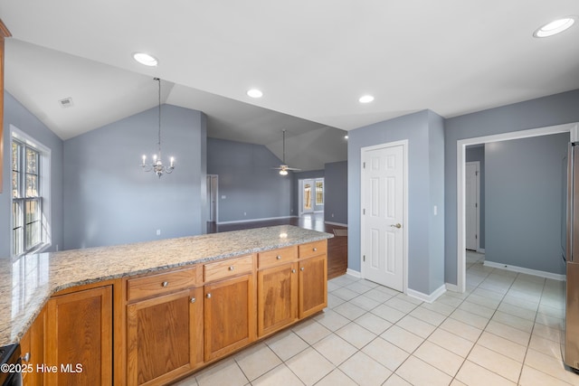 kitchen with lofted ceiling, hanging light fixtures, plenty of natural light, and light stone countertops