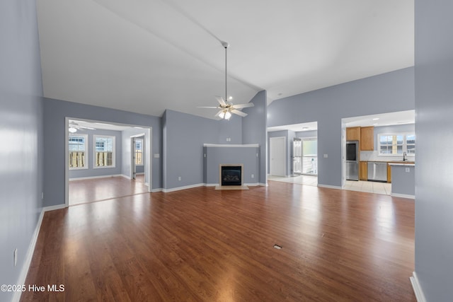 unfurnished living room with sink, a wealth of natural light, ceiling fan, and light hardwood / wood-style floors