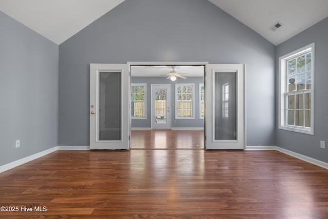 spare room featuring dark wood-type flooring, high vaulted ceiling, and plenty of natural light