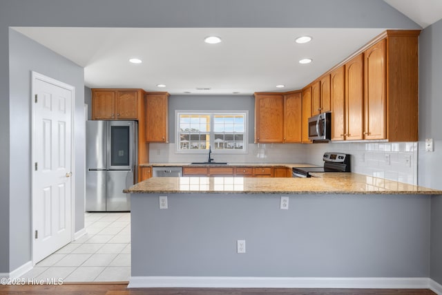 kitchen featuring stainless steel appliances, light stone countertops, kitchen peninsula, and light tile patterned floors