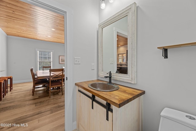 bathroom with sink, wood ceiling, wood-type flooring, and toilet