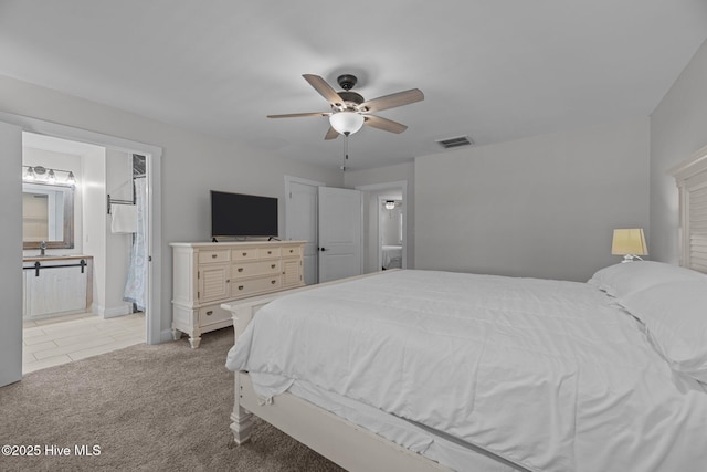 bedroom with ceiling fan, connected bathroom, and light carpet