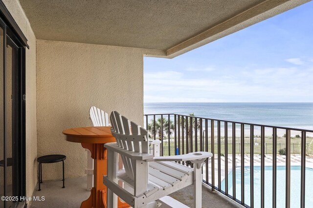 view of pool with a patio area, a water view, and a view of the beach