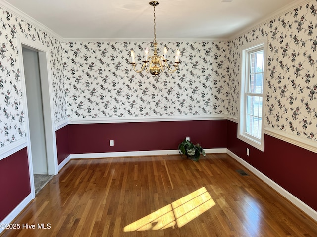 unfurnished room featuring wood-type flooring, crown molding, and a chandelier