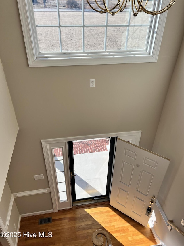 entrance foyer featuring wood-type flooring, an inviting chandelier, and a healthy amount of sunlight