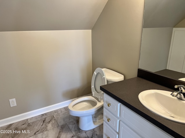 bathroom featuring toilet, vanity, and vaulted ceiling