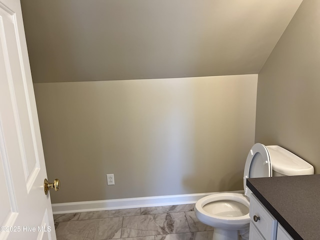 bathroom featuring toilet, vanity, and vaulted ceiling