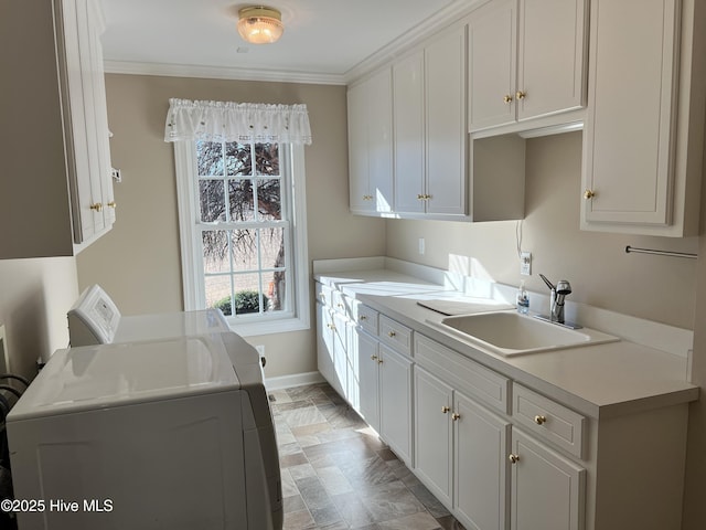 kitchen featuring washer and dryer, crown molding, white cabinets, and sink