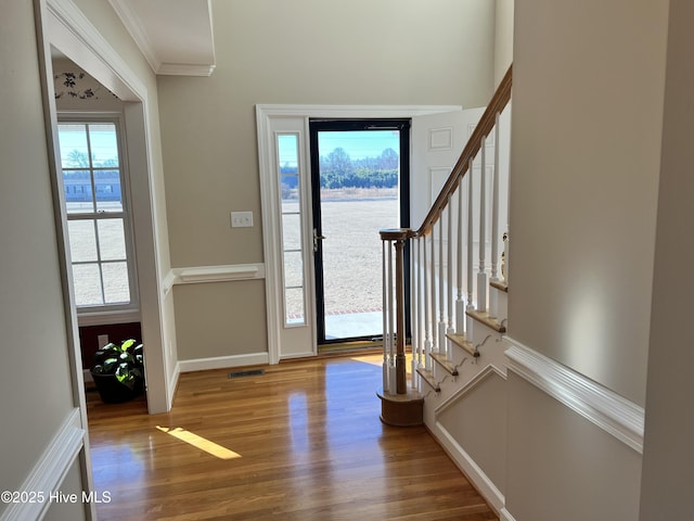 foyer entrance featuring a wealth of natural light, crown molding, and hardwood / wood-style floors