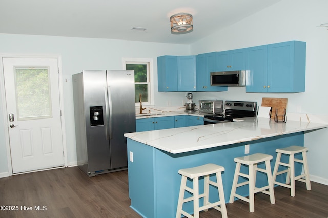 kitchen with kitchen peninsula, appliances with stainless steel finishes, blue cabinetry, and sink